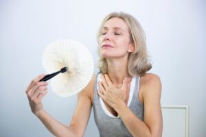 Woman experiencing a hot flash, a common symptom of hormonal imbalance often discussed in relation to menopause and hormone replacement therapy (HRT).