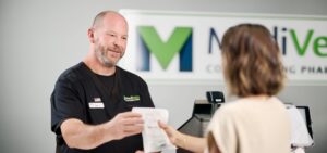 Pharmacy technician handing a liraglutide prescription to a customer.