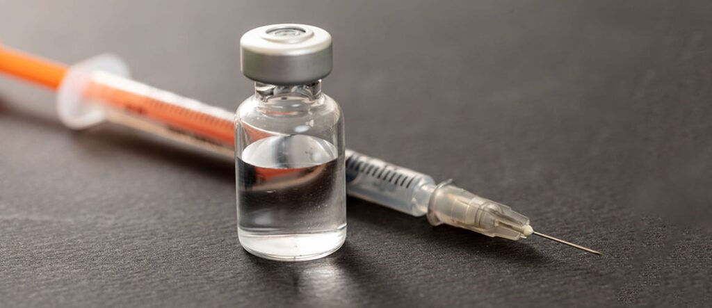 A syringe beside a vial of clear liquid.